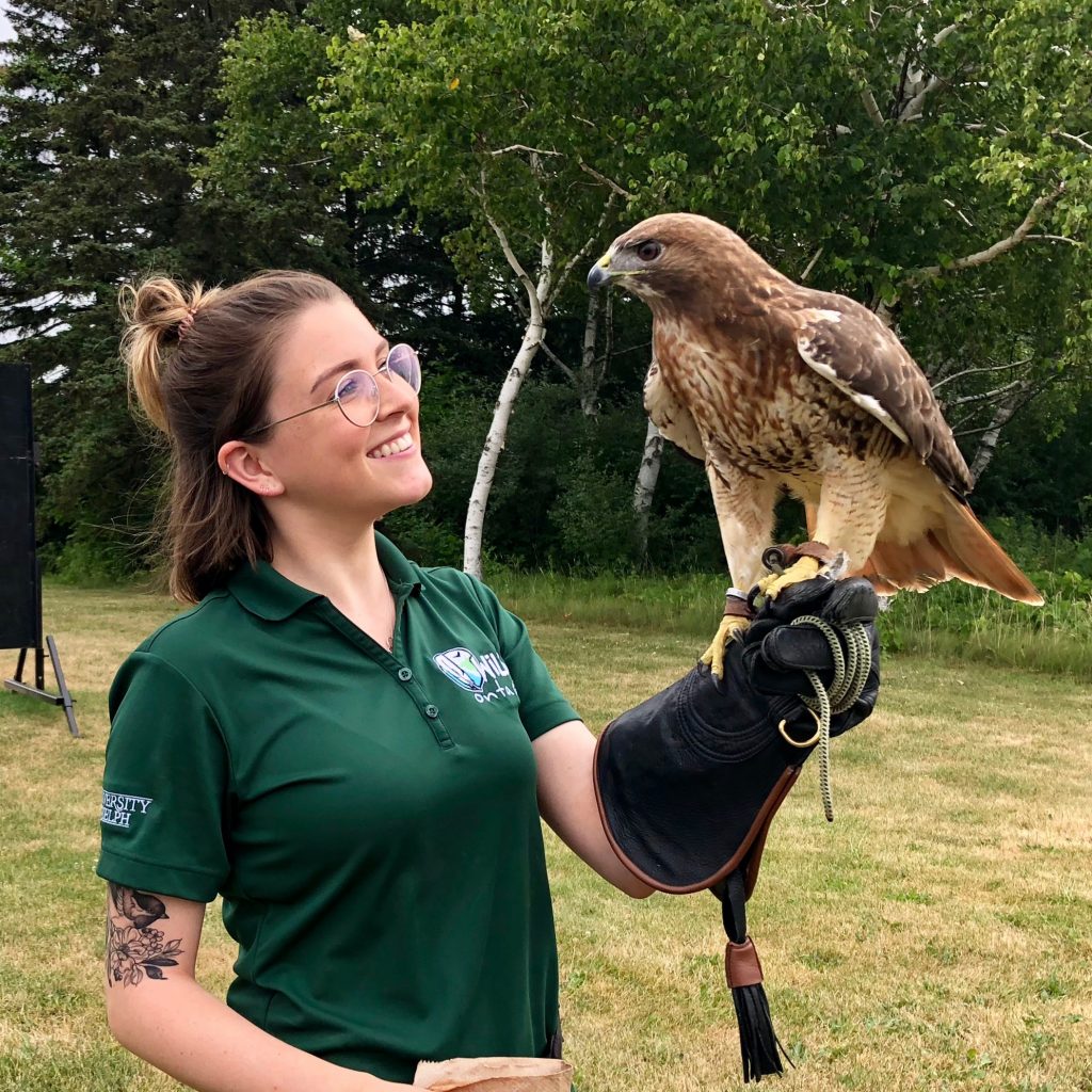 A university student standing with a hawk.